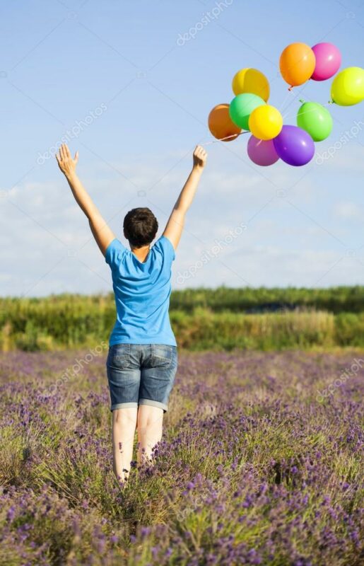 Frau von hinten mit Luftballons vor blauem Himmel